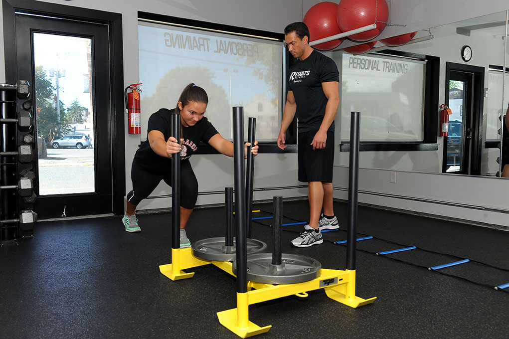 Woman pushing sled in gym